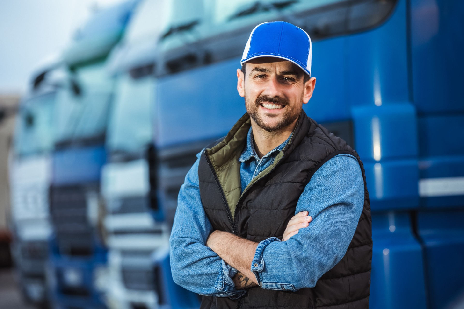 Happy confident male driver standing in front of his truck.